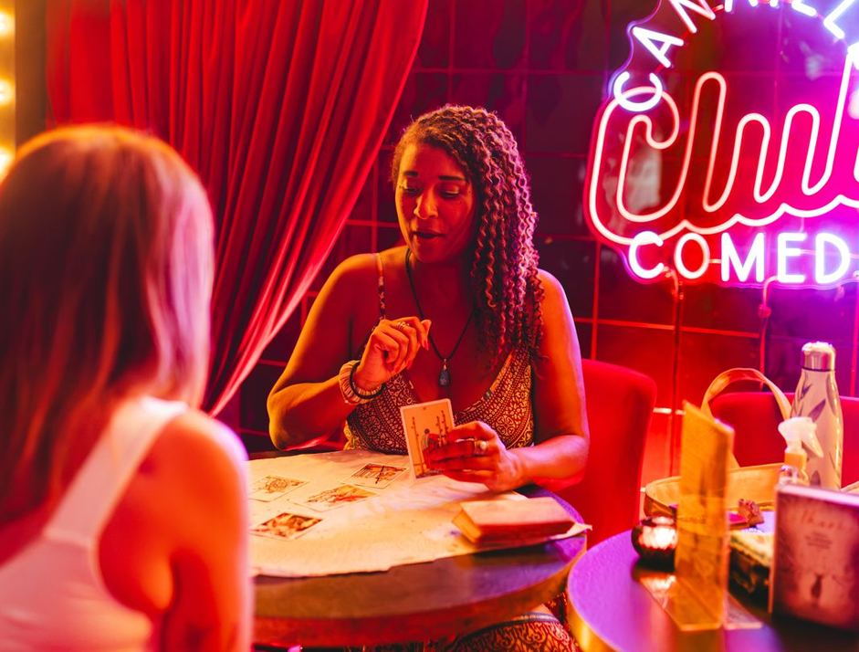 Johanna qui tire les cartes pour une invitée lors d'une soirée, dans une ambiance de club