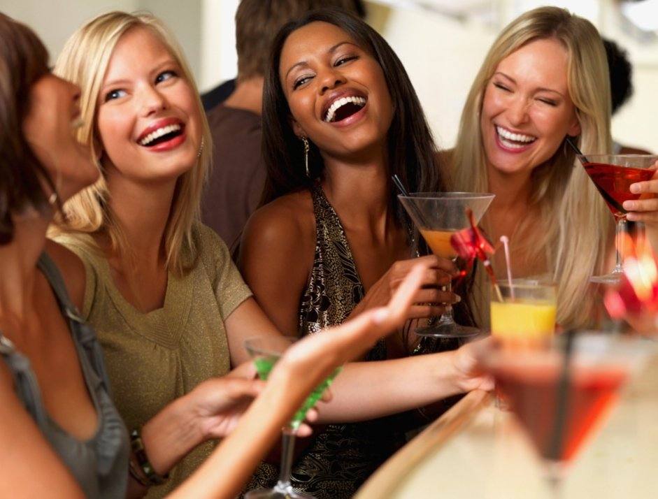 Invitées qui rient ensemble, un verre à la main, lors d'une soirée