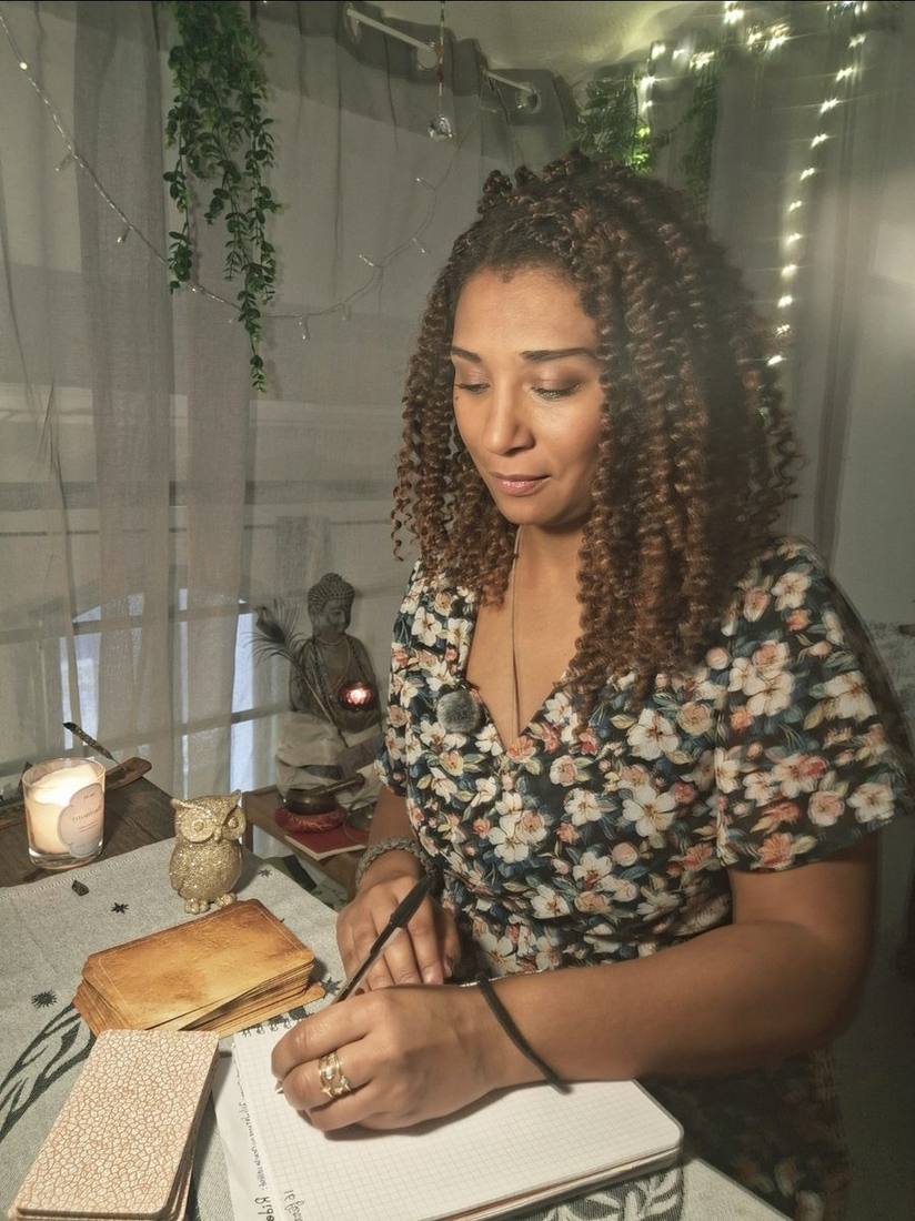 Johanna pendant une guidance, carnet ouvert et cartes posées près d'une bougie